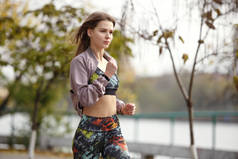 年轻运动的女孩在城市公园慢跑在秋天天.