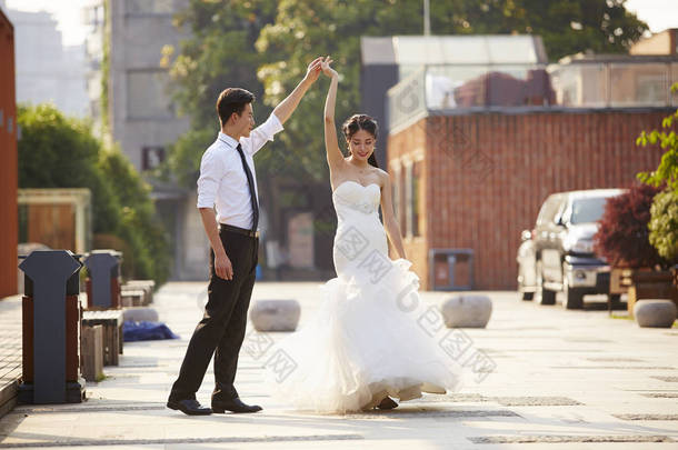 亚洲新娘和新郎在停车场中跳舞