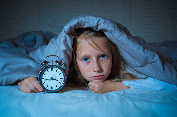 可爱的不眠之夜的小女孩在床上醒着在半夜看