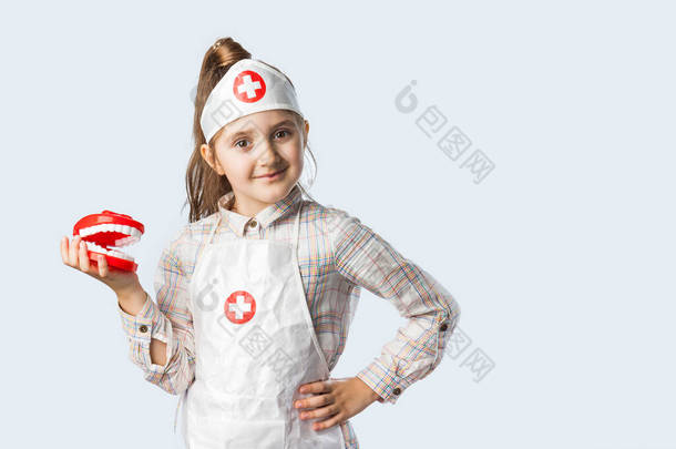小酷医生牙医女孩在医疗服与玩具下巴和牙刷