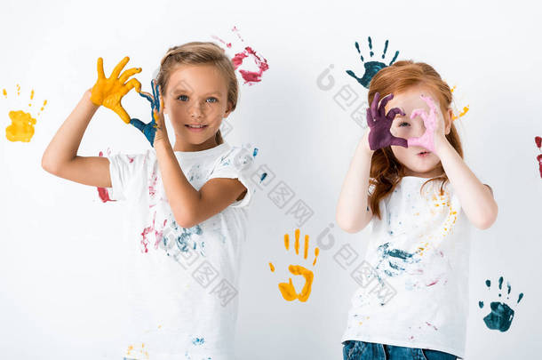 快乐的孩子们手握五彩斑斓的白漆，展示着心形的标志 