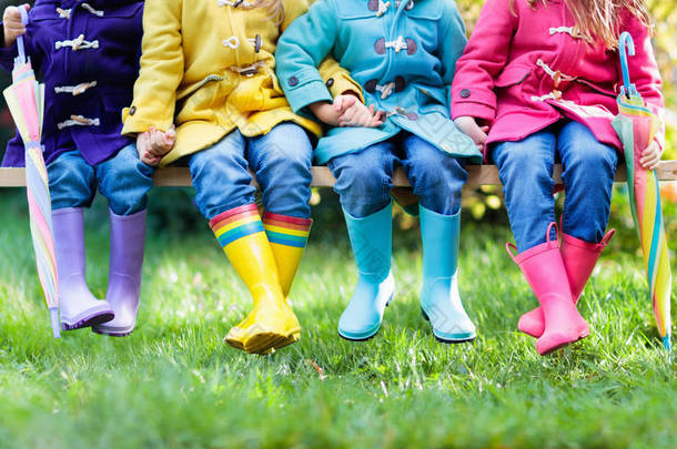 一群穿着雨鞋的孩子。五颜六色的儿童鞋。男孩和女孩在彩虹雨靴和粗<strong>大衣</strong>。秋季或冬季的彩虹脚穿和衣服。阴雨天气外衣和<strong>时尚</strong>.