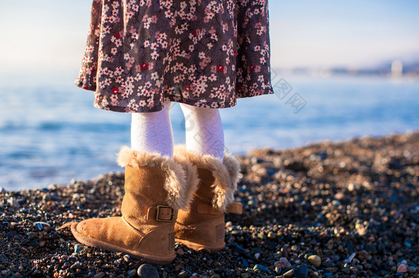 特写的腿在舒适的毛皮靴子背景下的小女孩海