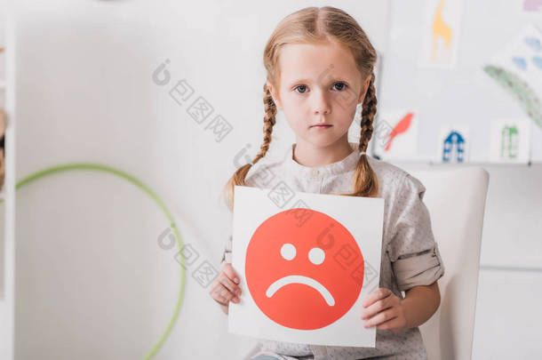 一个孤独的小孩拿着悲伤的脸符号的特写镜头