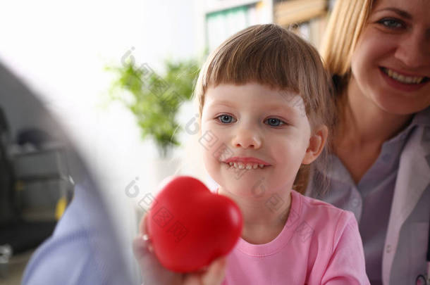 小女孩访问医生手红色玩具心脏