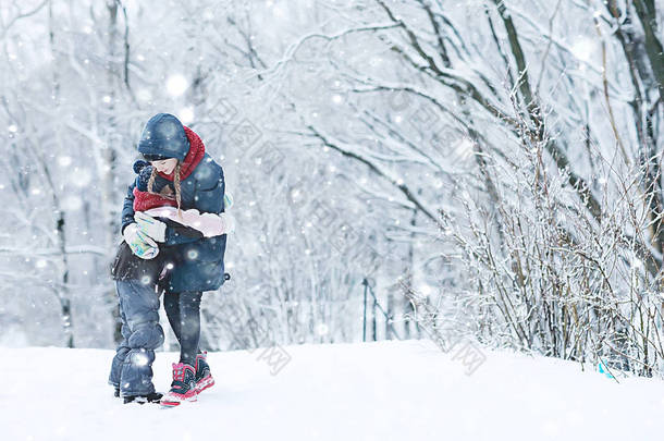 两个小女孩在冬季公园玩雪。童年、友谊、家庭的概念