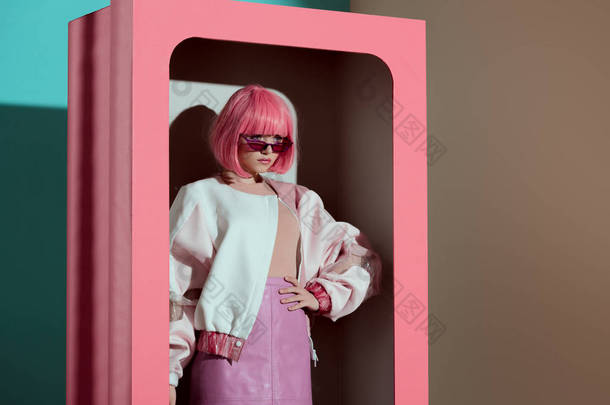 美丽的时尚女孩在粉红色的假发与手在装饰盒腰部摆在一起 