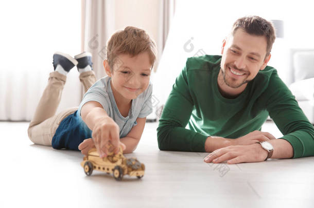 可爱的小男孩和爸爸在家里的地板上玩玩具车