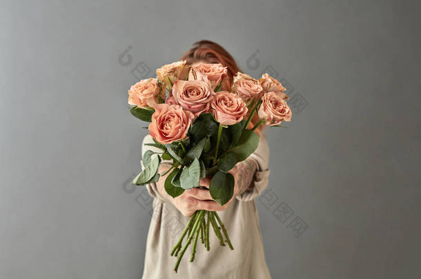 年轻的红头发的女人拿着一束卡布奇诺玫瑰对灰色背景和覆盖面, 母亲节概念
