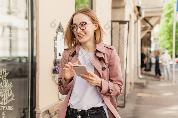 快乐的微笑的女商人使用现代智能手机设备, 成功的女企业家使用手机无线连接沿街走, 年轻女子浏览手机外