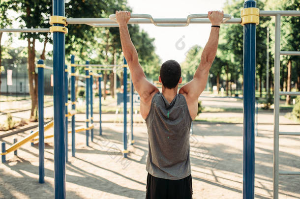 运动男子在水平杆上做拉运动, 户外健身锻炼。强运动员在公园体育训练