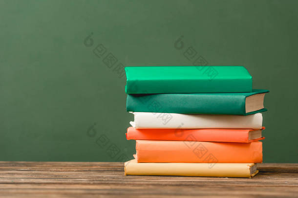 一叠五颜六色的书在木制表面隔离在<strong>绿色</strong>