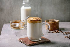 达尔戈纳泡沫咖啡趋势韩国人喝牛奶拿铁与咖啡泡沫在玻璃杯，装饰地面咖啡灰色质感表。上面的成份。复制空间