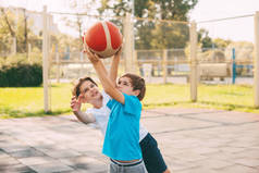 两个少年在操场上打篮球.运动员在比赛中为争取球而奋斗.健康的生活方式、运动、动机