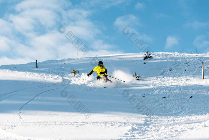 戴头盔的运动员在室外斜坡滑雪时拿着滑雪棍 