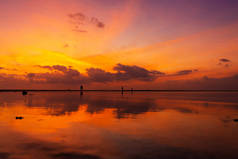 日落时分,热带海滩上燃烧着明亮的天空.大逃亡中的夕阳西下，人们在水上行走的力量.