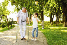 一个男孩和一个老人踩高跷在公园散步