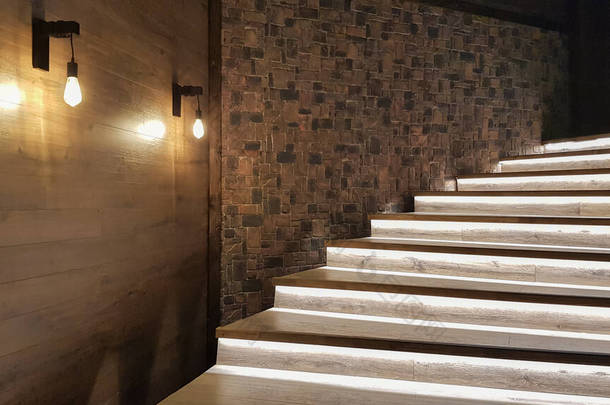 灯火通明的楼梯，有木制台阶，晚上在大房子的内部点亮.