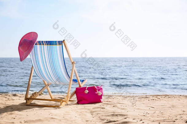 <strong>休闲椅</strong>、帽子和包在海边的沙上，有文字空间。海滩对象