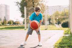 以可爱的男孩运动员为焦点,在篮球比赛中带领球前进.一个男孩放学后打篮球.体育、健康的生活方式、休闲