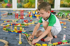 小孩子在地板上玩木制铁路。小男孩玩木火车集