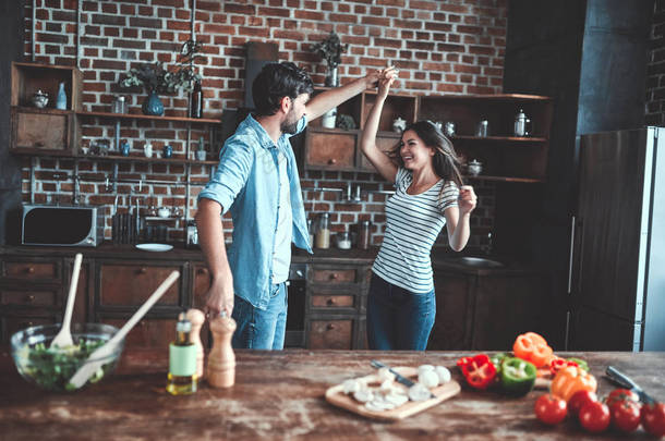 浪漫情侣在厨房做饭。英俊的男人和有魅力的年轻女人在一起做沙拉时玩得很<strong>开心</strong>。健康的生活方式概念.