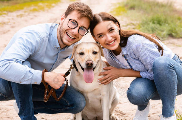 一对快乐的年轻夫妇抱着他们可爱的狗的画像