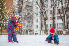 快乐的兄妹在冬天散步时玩雪球, 在公园里做雪球。冬季户外运动.