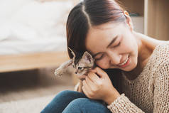 年轻的亚洲女人抱着可爱的小猫玩耍，有着可爱的时刻，可爱的宠物和人类的概念