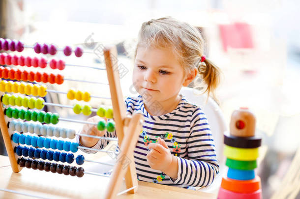 可爱的可爱的可爱的小幼儿女孩玩教育木制彩虹<strong>玩具</strong>金字塔和反算盘。健康快乐的婴儿学习计数和颜色，在阳光明媚的日子在室内.