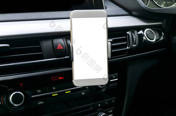 在导航或 Gps。 驾驶一辆带有智能手机持有人在车上使用的智能手机。孤立的白色屏幕的手机。空白的空白屏幕。复制空间。文本的空白空间。现代汽车内部的细节.