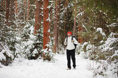 一个人背着背包旅行。森林里的冬季远足。冬天在公园里散步的游客.