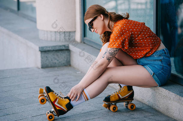 坐在街上的戴着轮滑鞋的年轻女子的侧面观察