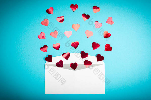 红色的五彩纸屑心在浅蓝色的背景下从白色的信封里飞出。情人节。爱的概念<strong>送给</strong>爱人的礼物