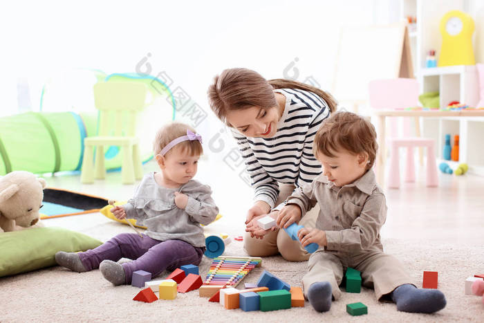 年轻保姆读书给可爱的小孩子在床上