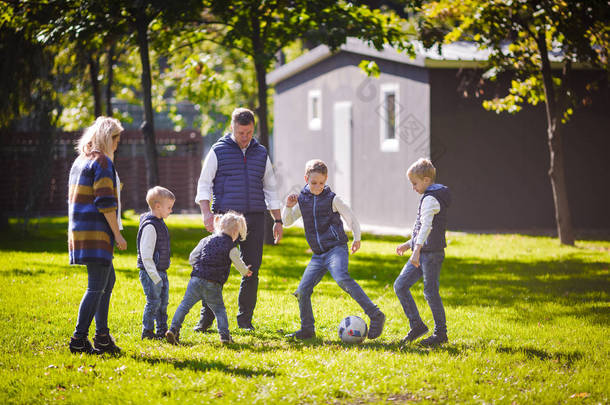 主题家庭户外活动。大友好的白种家庭六妈妈爸爸和四孩子踢足球, 运行与球在草坪上, 绿色草坪草坪附近的房子在阳光明媚的一天.