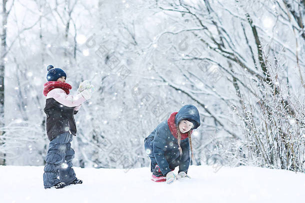 两个小女孩在冬季公园玩雪。童年、友谊、<strong>家庭</strong>的概念