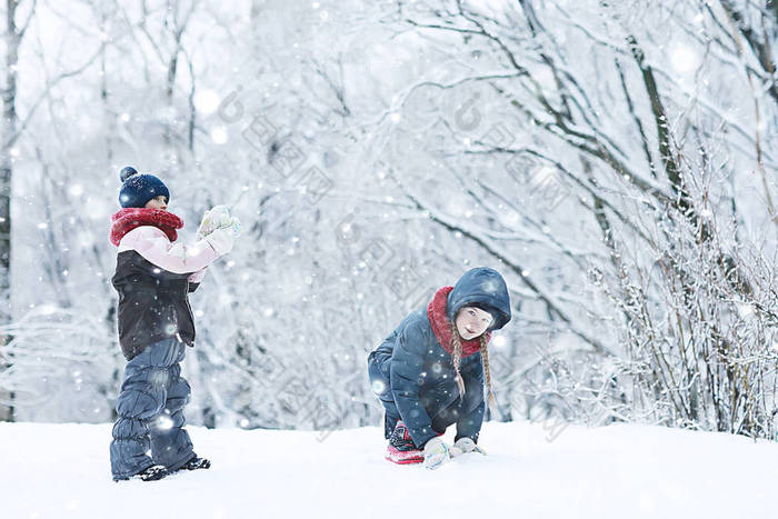 两个小女孩在冬季公园玩雪。童年、友谊、家庭的概念