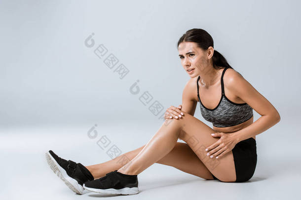 有吸引力的黑发女运动员与膝盖<strong>疼痛</strong>灰色