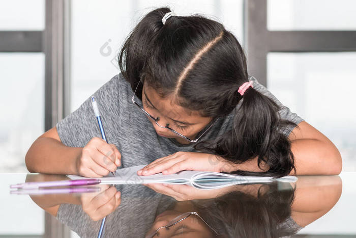 小学亚洲女学生在课桌上写作业的教育观念 