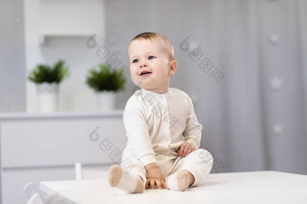 一个小男孩的画像。婴儿坐在一间明亮的房间里.