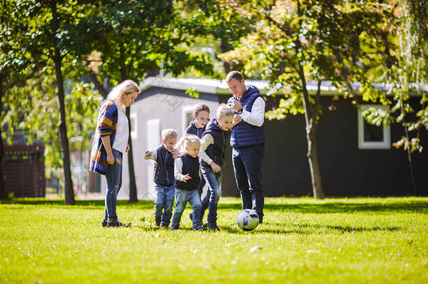主题家庭户外活动。大友好的白种家庭六妈妈爸爸和四孩子踢足球, 运行与球在草坪上, 绿色草坪草坪附近的房子在阳光<strong>明媚</strong>的一天.