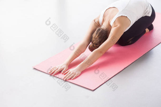 年轻女子做瑜伽, 躺在儿童姿势在健身房 