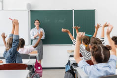 后见多文化学生手牵手在空中，老师站在黑板旁边，背对着学校的字母