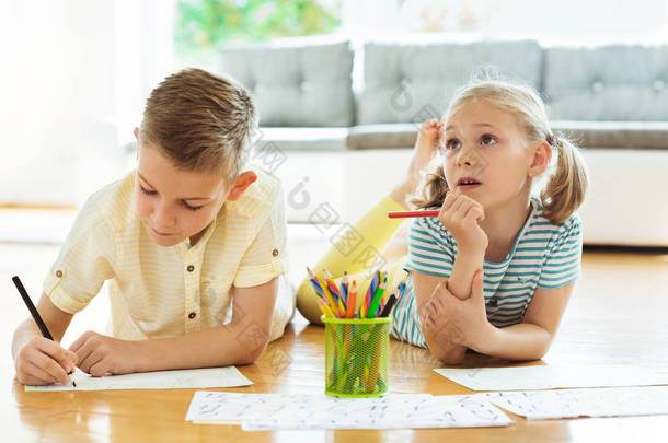 两个<strong>可爱</strong>的孩子在家里用五颜六色的铅笔画画