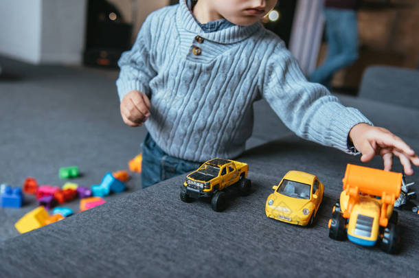 部分观看男孩在家里的客厅里玩玩具车的情况