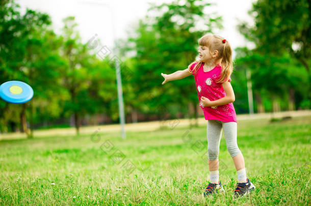 小女孩在运动中玩飞行盘, 在夏季公园玩休闲活动游戏