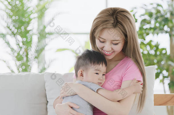 妈咪拥抱她的儿子和愉快地微笑在家中