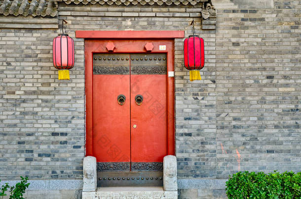 中国北京传统的胡同，古董店的门上挂着红色的灯笼，是一座古老的砖楼