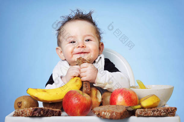 可爱的男孩吃健康食物为早餐在明亮的蓝色背景: 水平